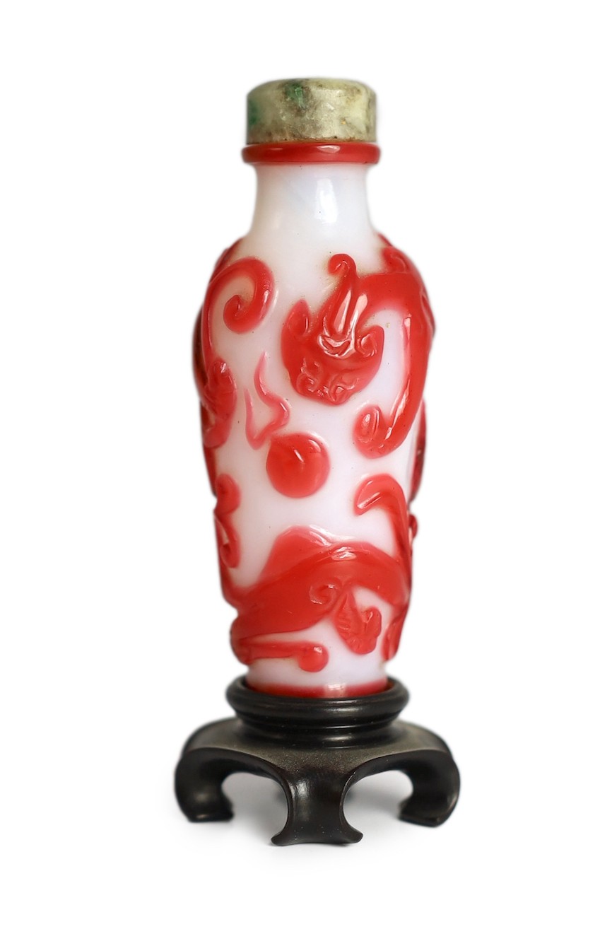 A Chinese red overlay on white glass ‘chilong’ snuff bottle, 1780-1850, 6.5cm high, wood stand